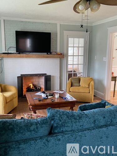 A living room with a blue velvet couch and a television above a fireplace.