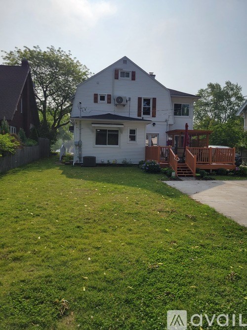 A white house with a brown deck in the backyard.