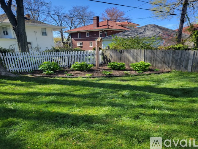 A backyard with a white picket fence and a red house.