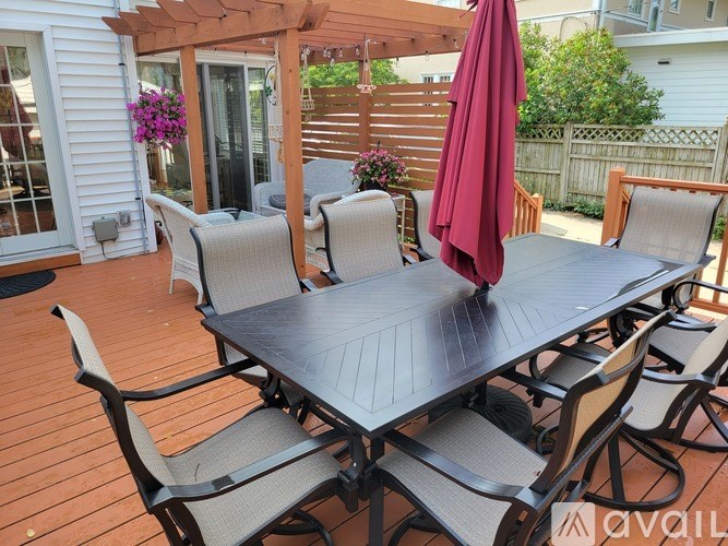 A table with chairs and an umbrella on a wooden deck.