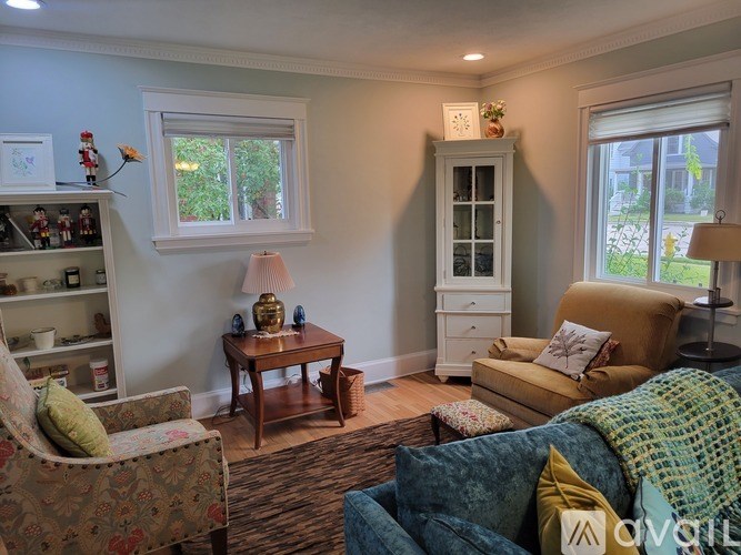 A living room with a sofa, armchair, and a table with a lamp.