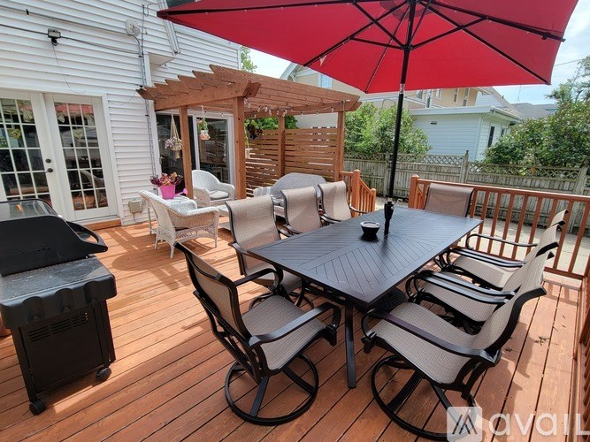 A patio with a table and chairs under a red umbrella.
