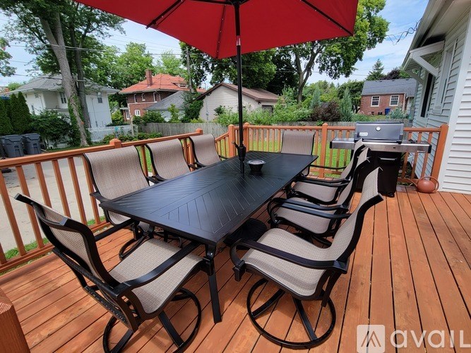 A table with chairs and an umbrella on a deck.