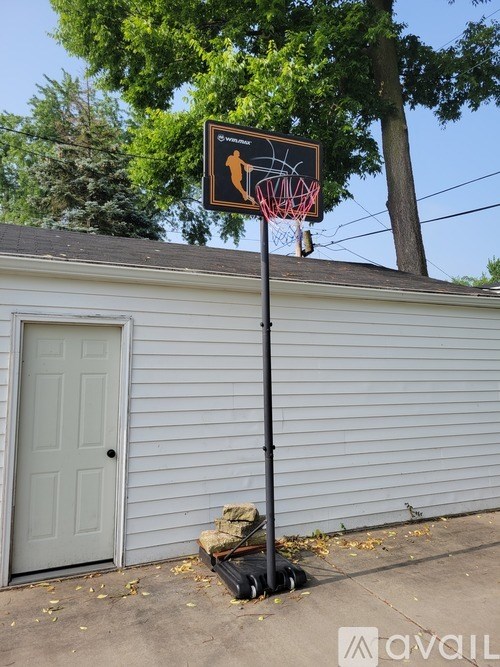 A basketball hoop is mounted on a pole in front of a house.