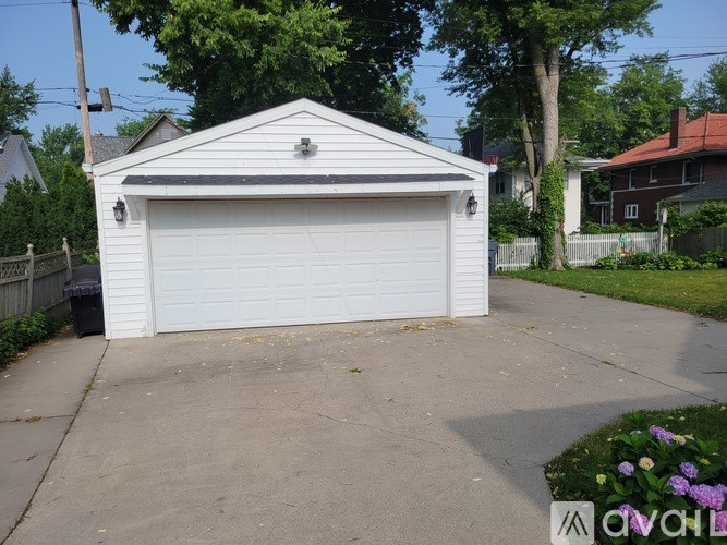 A white garage door is closed and the garage is situated in a driveway.