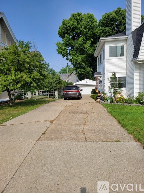 A car is parked on a driveway in front of a white house.
