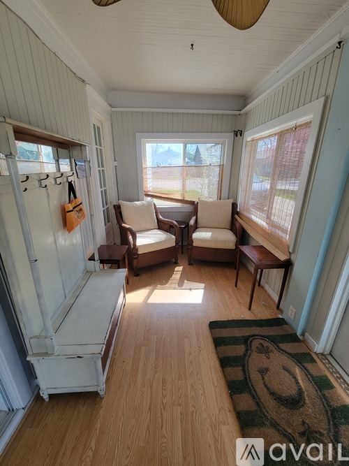 A sunny day in a room with a couch, chair, and rug.