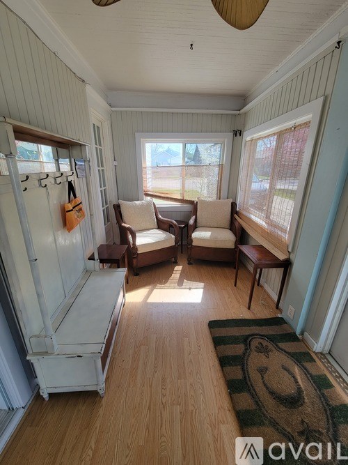 A sunny day in a room with a couch, chair, and rug.