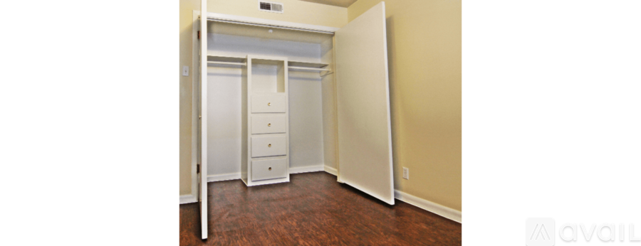 A bedroom with a white closet and wooden floors.