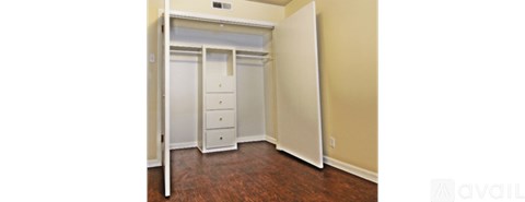 A bedroom with a white closet and wooden floors.