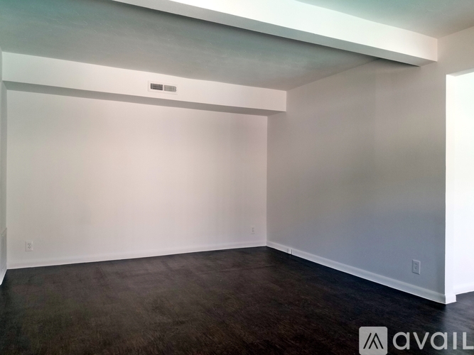 A spacious room with a dark floor and white walls.