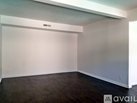 A spacious room with a dark floor and white walls.