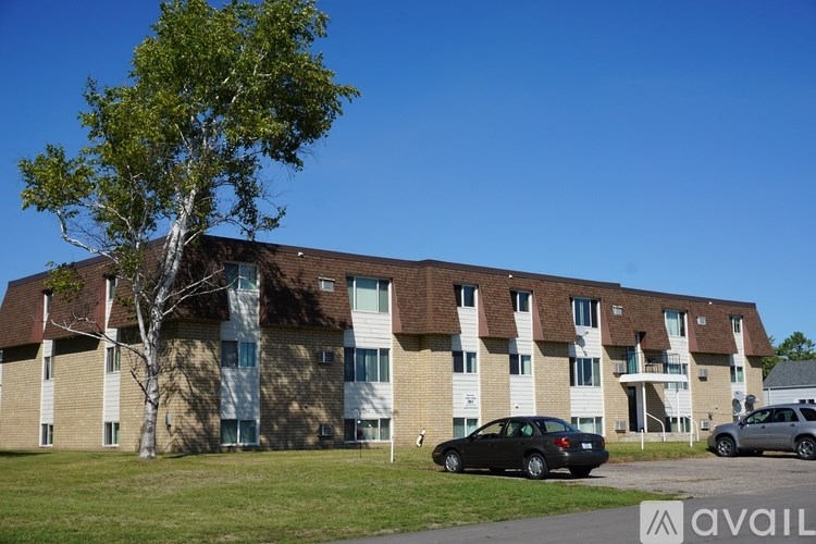 A black car is parked in front of a building with a tree in front of it.