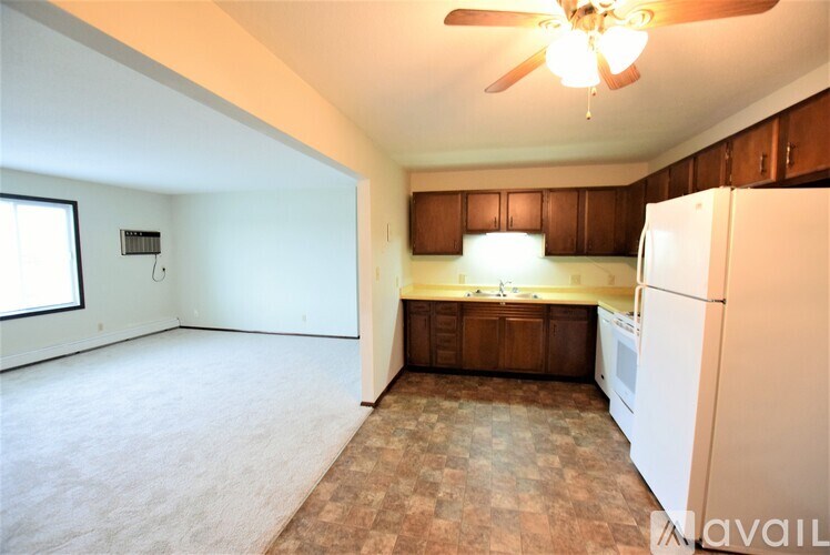 A kitchen area with a refrigerator, microwave, and wooden cabinets.