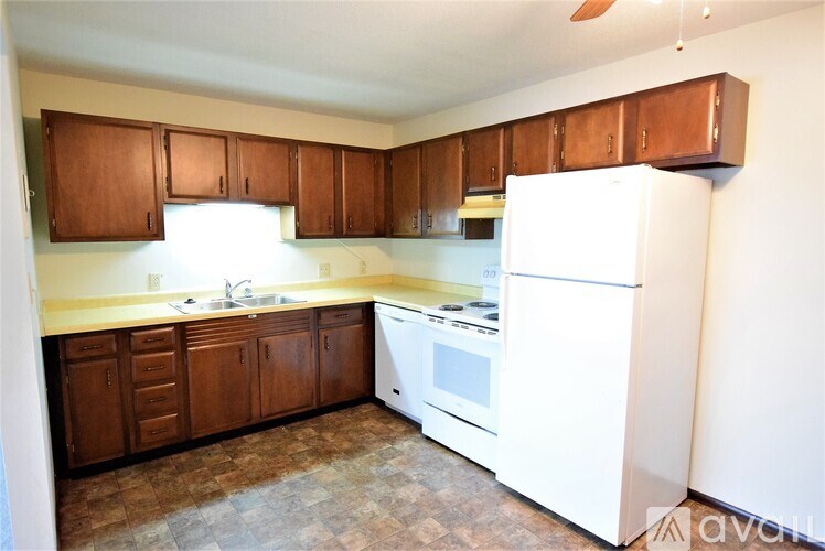 A kitchen with white appliances and wooden cabinets.