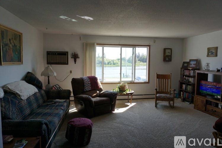 A living room with a couch, chair, ottoman, and television.