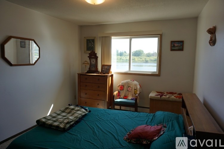 A bedroom with a bed, dresser, and window.