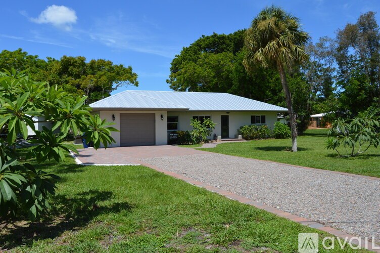 A house with a blue roof and a driveway in front.