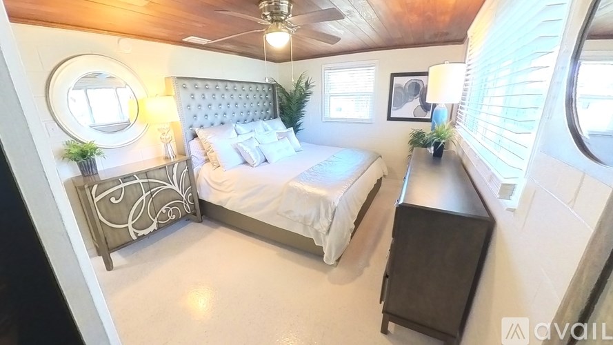 A bedroom with a bed, nightstand, and a round mirror on the wall.