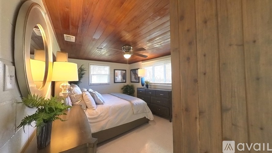 A bedroom with a bed, dresser, and a plant.