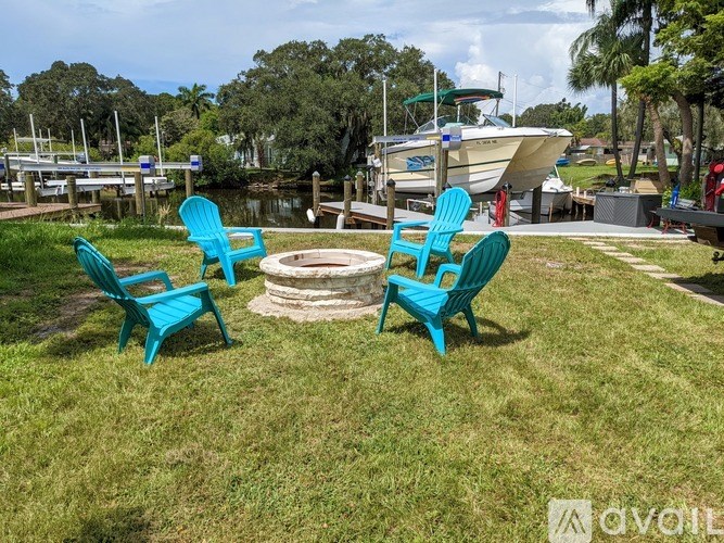 A lawn with two blue chairs and a fire pit.