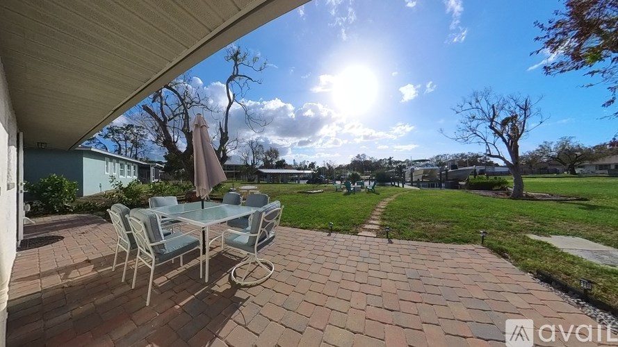 A patio with a table and chairs is in the foreground with a sunny sky above.