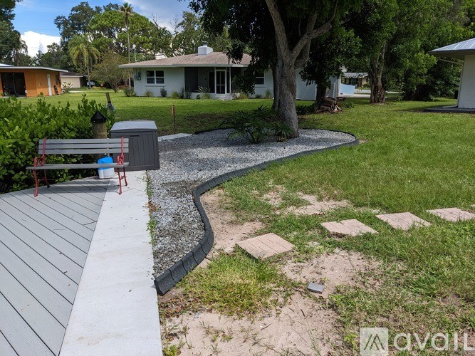 A backyard with a wooden deck and a gravel path.