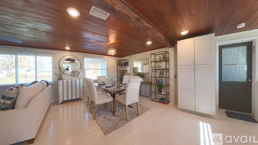 A modern living room with a wooden ceiling and white furniture.