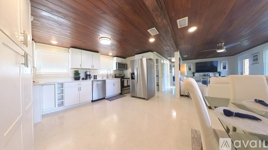 A spacious kitchen with white cabinets and a wooden ceiling.