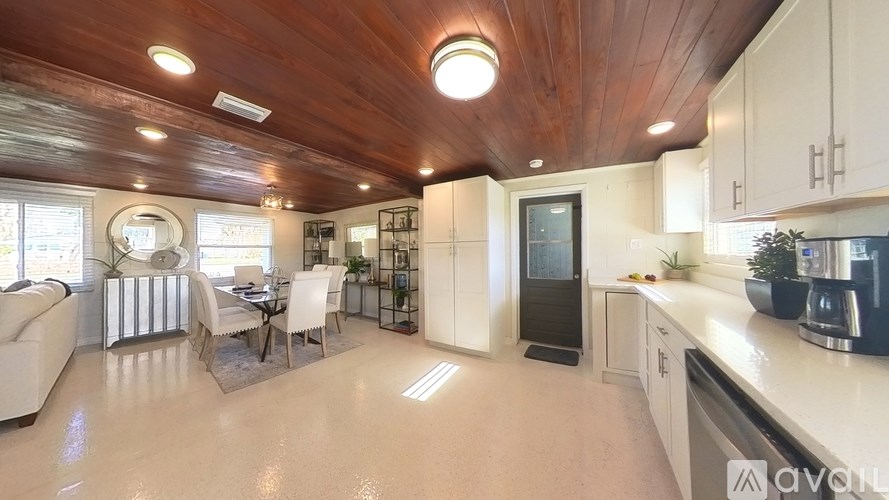 A modern kitchen with a wooden ceiling and white cabinets.
