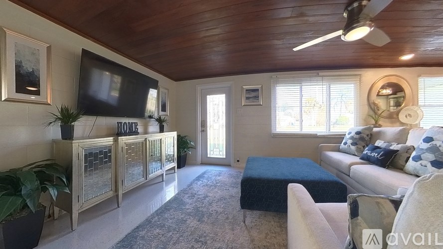 A living room with a couch, a television, and a fan.
