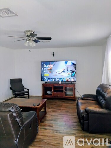 A living room with a television and a fan.