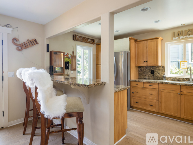 A kitchen with a bar stool and a chair with a white fluffy cushion.