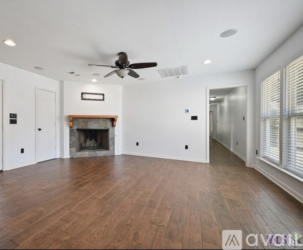 A spacious room with a fireplace and wood flooring.