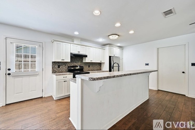 A kitchen with white cabinets and a wooden floor.