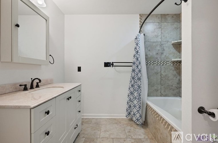 A bathroom with a white cabinet and a shower with a glass door.