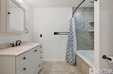 A bathroom with a white cabinet and a shower with a glass door.