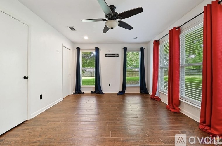 A room with a ceiling fan and sliding glass doors.