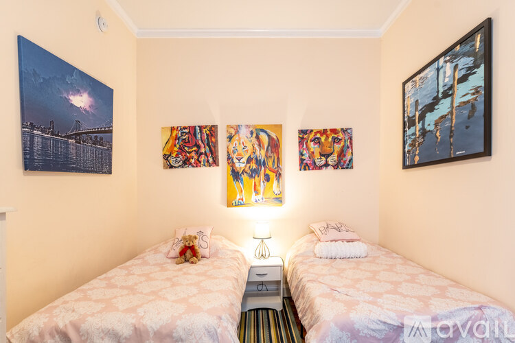 A bedroom with two beds and artwork on the wall.