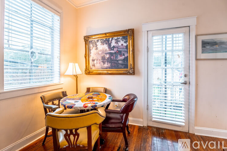 A dining room with a table set for six and a painting on the wall.