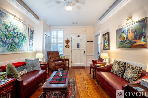 A living room with a red couch and a painting on the wall.