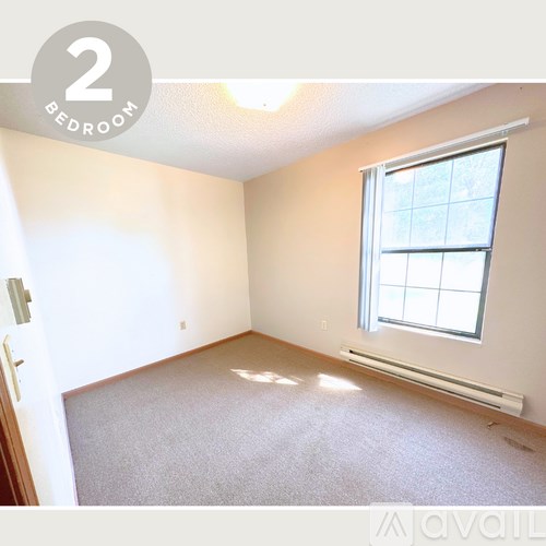 A bedroom with a window and carpeted floor.