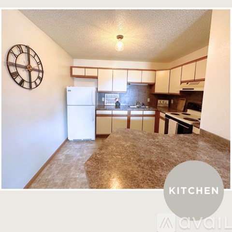 A kitchen with a white refrigerator and a clock on the wall.