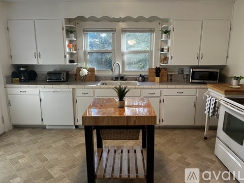 A kitchen with white cabinets and a wooden table.
