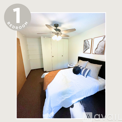 A bedroom with a bed, a ceiling fan, and a cabinet.