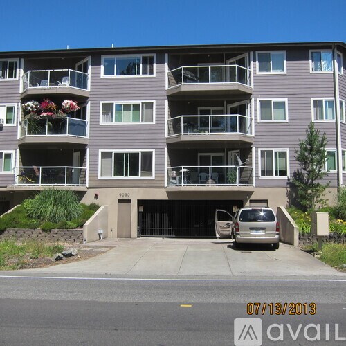 A grey apartment building with a car parked in front.