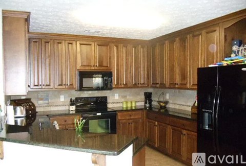 A kitchen with wooden cabinets and black appliances.
