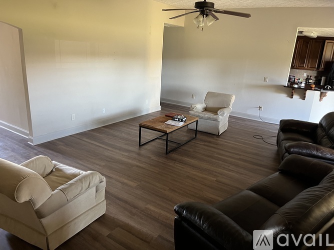 A living room with a white couch, a black leather couch, and a wooden coffee table.