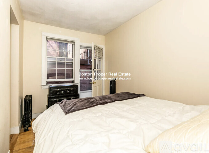 A bedroom with a bed, nightstand, and window.