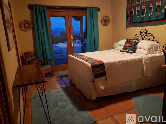 A bedroom with a large bed and a view of the outdoors through a sliding glass door.